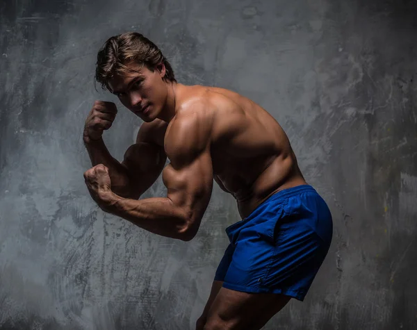 Awesome shirtless bodybuilder in blauwe korte broek. — Stockfoto
