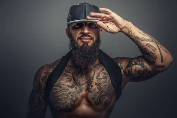 Βάναυση τατουάζ άνδρας στο μαύρο καπάκι. — Φωτογραφία Αρχείου