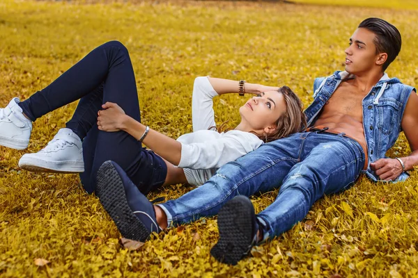 Молода пара лежить на трав'яному полі . — стокове фото