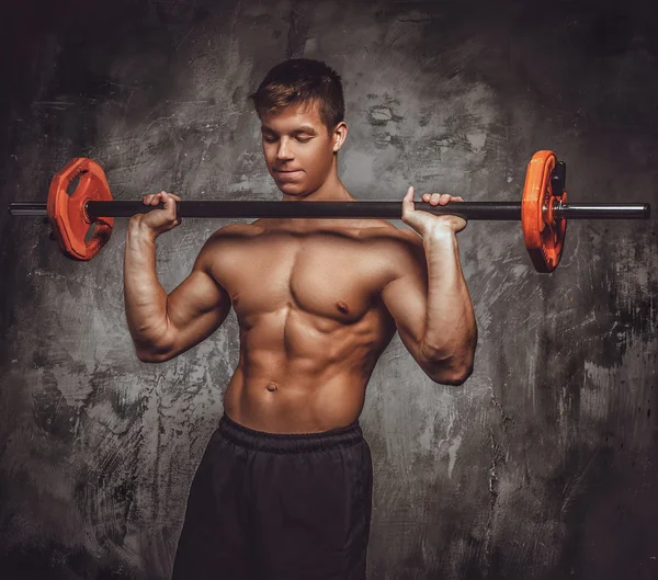 Shirtles muscular jovem cara detém barbell . — Fotografia de Stock