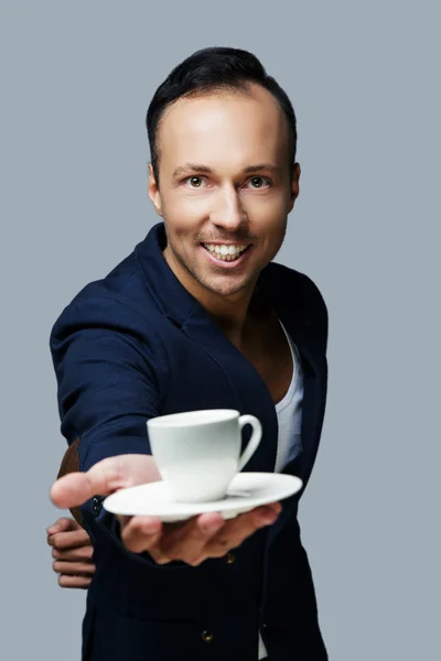 Elbiseli adam gülümsüyor tutar beyaz kahve fincanı. — Stok fotoğraf