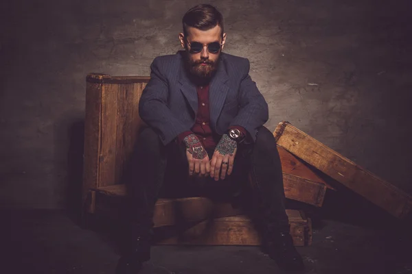Man in sunglasses sits in dark light. — Stock Photo, Image