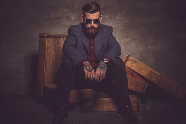 Hombre en gafas de sol se sienta en la luz oscura . — Foto de Stock