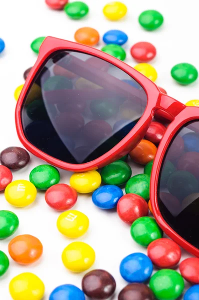 Rote Sonnenbrille und viele bunte runde Bonbons — Stockfoto