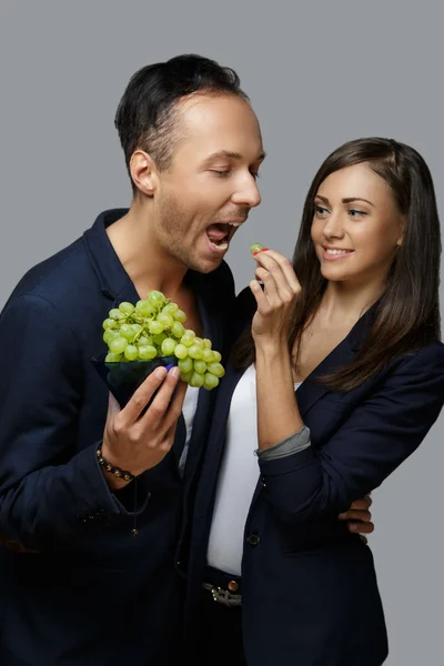 Woman feeds man with green grape. — Stock Photo, Image