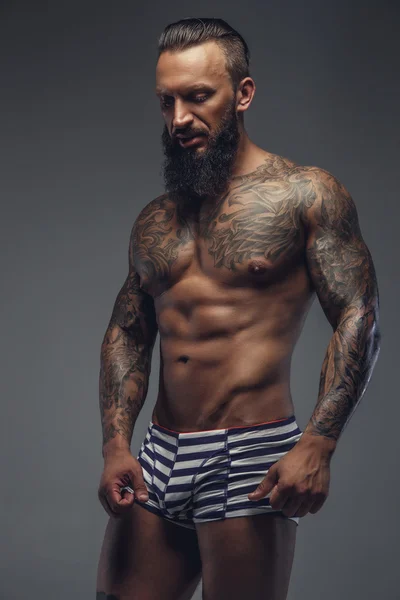 Un hombre con tatuajes en su cuerpo . — Foto de Stock