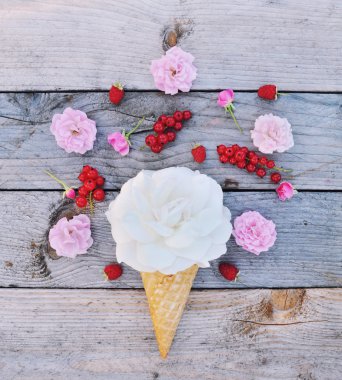 Beyaz gül çiçek ve olgun kırmızı kuş üzümü Dondurma külahı rustik ahşap zemin üzerinde. Şık düz yatıyordu. En az kavramı.