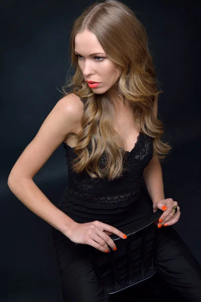 Beautiful woman in a black evening dress posing with chair — Stock Photo, Image