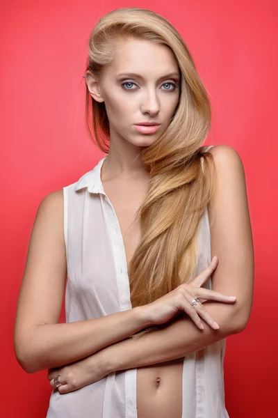 Mooie seminude blonde vrouw op rode achtergrond. — Stockfoto