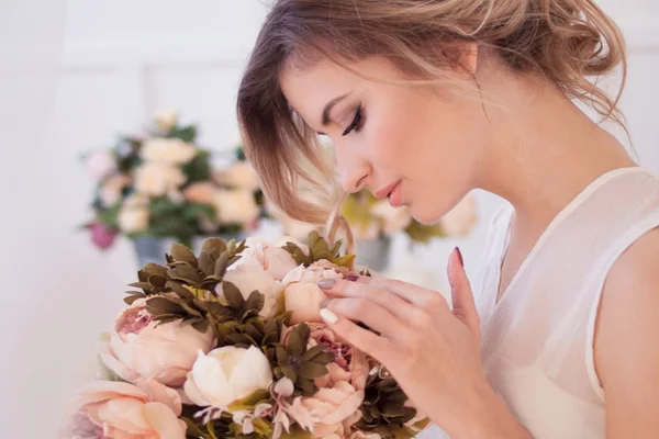 Beau modèle de femme avec maquillage frais quotidien et coiffure romantique ondulée, tenant un bouquet de fleurs — Photo