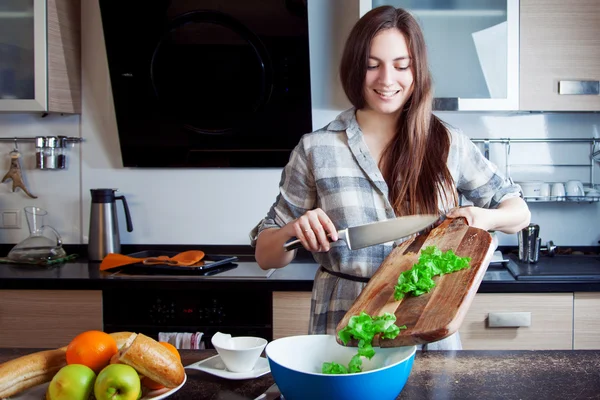 Young woman cut salad and put it in a big plate — Stock fotografie