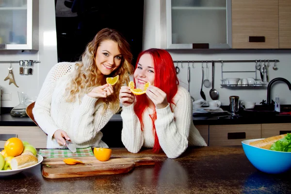 Két fiatal lány a konyhában, beszél, és eszik gyümölcsöt, egészséges életmód — Stock Fotó