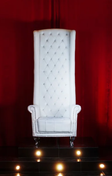 Trono blanco sobre fondo rojo, silla con respaldo alto, posición elevada —  Fotos de Stock