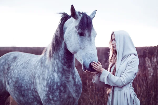 Chica en la capa encapuchada con caballo, efecto de tonificación — Foto de Stock