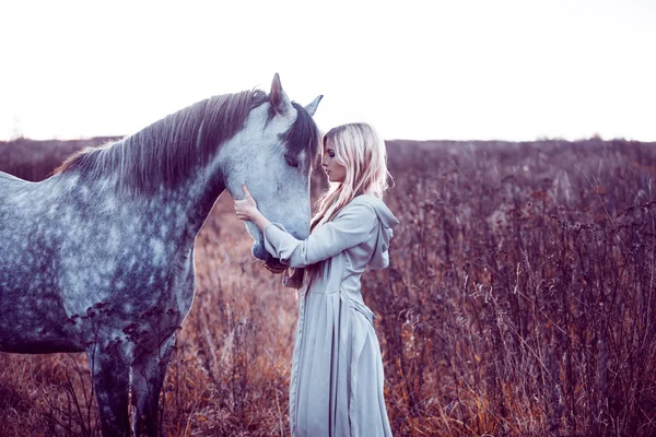 Loirinha de beleza com cavalo no campo, efeito de tonificação — Fotografia de Stock