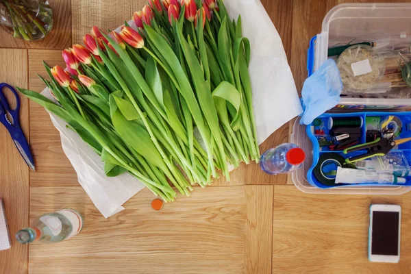 Lieu de travail fleuriste, nature morte avec bouquet de tulipes, ciseaux et outils — Photo