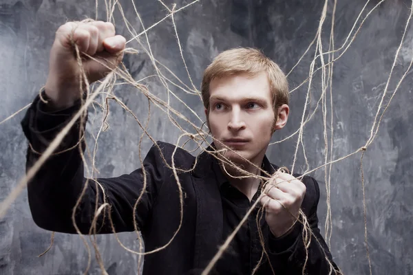 Der junge Mann versucht, die Fesseln zu lösen. Konzept der Manipulation und Sklaverei — Stockfoto