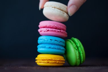 Yakın çekim siyah arka plan üzerinde renkli macaroons kule. El bir tanımlama bilgisi alır