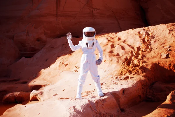 Um astronauta futurista num planeta arenoso, a acenar para a câmara. Imagem com efeito de tonificação — Fotografia de Stock