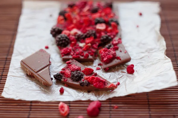 Handgemachte Schokolade mit frischen und getrockneten Beeren, Himbeeren, Erdbeeren, schwarzen Johannisbeeren, Brombeeren, Kakaopulver, auf rustikalem Holzgrund — Stockfoto