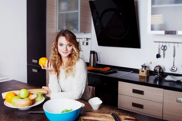 Mladá krásná žena v kuchyni. drží na oranžové v ruce, vyberte si zdravé výživy — Stock fotografie