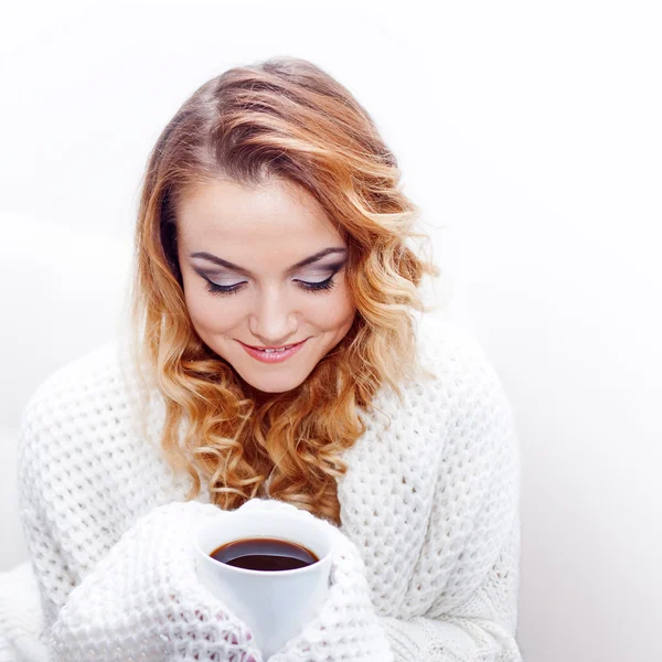 Giovane donna bionda attraente in un maglione caldo bere caffè caldo, sfondo bianco, posto per il tuo testo — Foto Stock