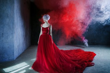 Kırmızı elbiseli genç muhteşem kadın moda fotoğrafı. Dokulu arka plan, duman