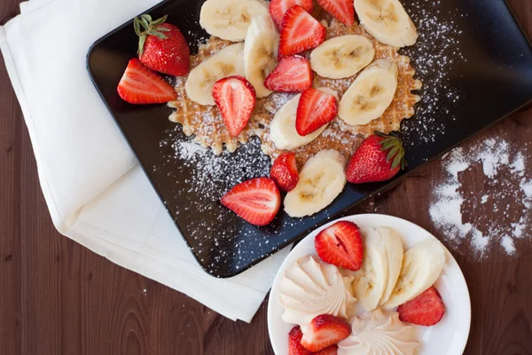 Våfflor med färska jordgubbar och bananer på rustika trä bakgrund. Ovanifrån — Stockfoto