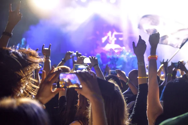 Personas tomando fotografías con el teléfono inteligente táctil durante un concierto público de entretenimiento musical, manos en el aire — Foto de Stock