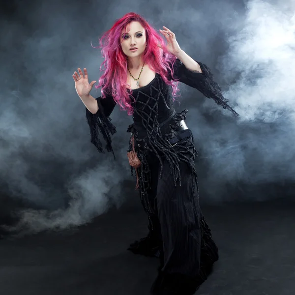 Bruja de Halloween crea magia. Mujer atractiva con el pelo rojo en traje de brujas —  Fotos de Stock