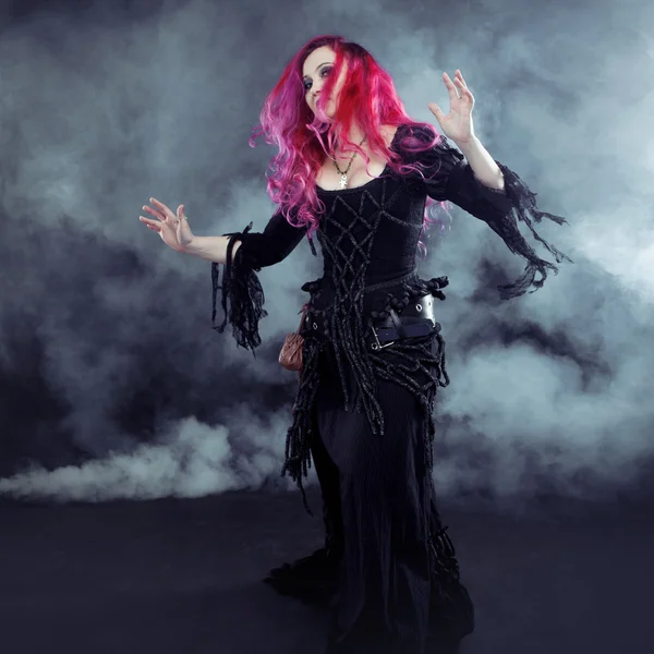 Halloween Witch creates magic. Attractive woman with red hair in witches costume — Stock Photo, Image