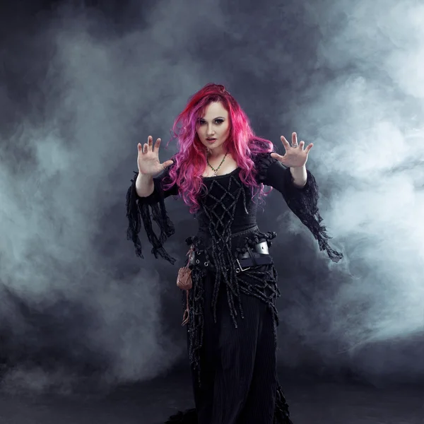Bruja de Halloween crea magia. Mujer atractiva con el pelo rojo en traje de brujas —  Fotos de Stock