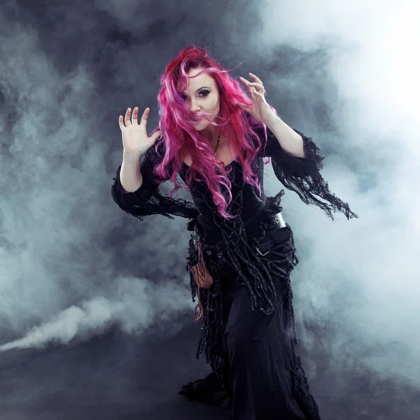 Bruja de Halloween crea magia. Mujer atractiva con el pelo rojo en traje de brujas — Foto de Stock