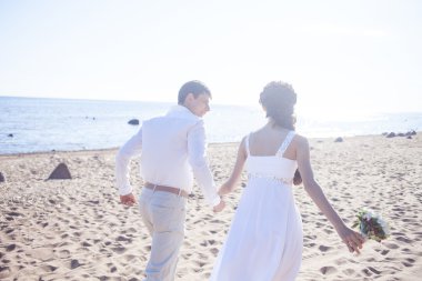 Kumlu bir plaj üzerinde çalışan sadece evli mutlu çift