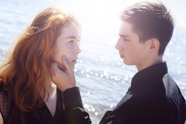 Beautiful young couple hugging standing in the sea, effect light — Stock Photo, Image