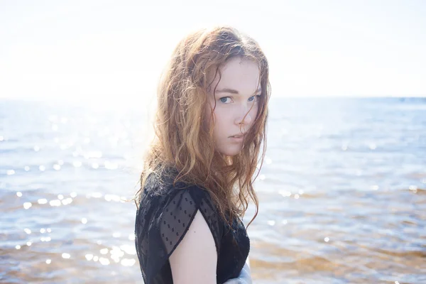 Mujer pelirroja joven al aire libre retrato en el fondo del mar. Colores suaves y soleados . — Foto de Stock