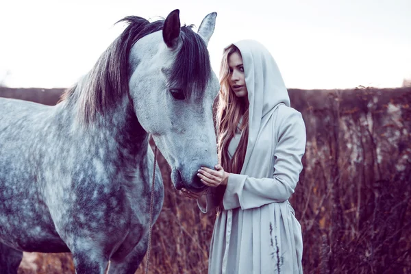 Chica en la capa encapuchada con caballo, efecto de tonificación — Foto de Stock