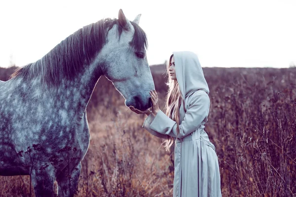 Chica en la capa encapuchada con caballo, efecto de tonificación —  Fotos de Stock