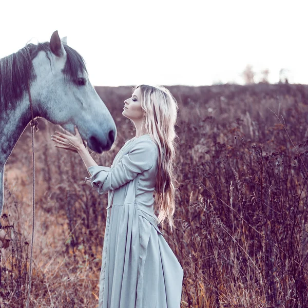 Menina no manto com capuz com cavalo, efeito de tonificação — Fotografia de Stock