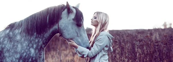 Menina no manto com capuz com cavalo, efeito de tonificação — Fotografia de Stock