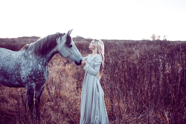 Menina no manto com capuz com cavalo, efeito de tonificação — Fotografia de Stock