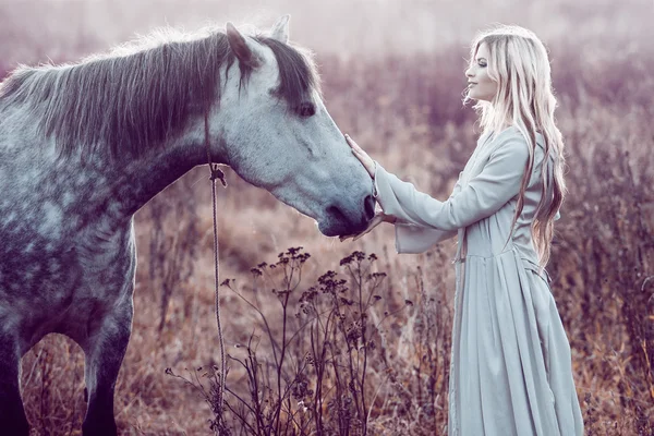 Chica en la capa encapuchada con caballo, efecto de tonificación — Foto de Stock