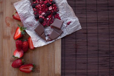 Taze ve kuru meyveler, ahududu, çilek, siyah kuş üzümü, böğürtlen, rustik tarzı ahşap zemin üzerine kakao tozu ile el yapımı çikolata