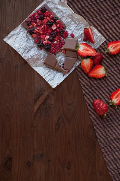 Handgemachte Schokolade mit frischen und getrockneten Beeren, Himbeeren, Erdbeeren, schwarzen Johannisbeeren, Brombeeren, Kakaopulver, auf rustikalem Holzgrund — Stockfoto