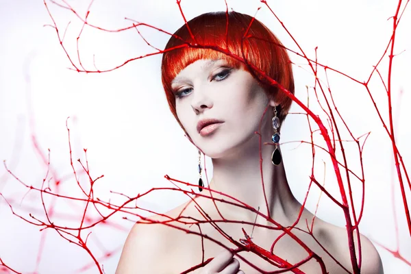 Fiatal gyönyörű vörös hajú nő. Fehér alapon, a fa ágait stúdióban portré — Stock Fotó