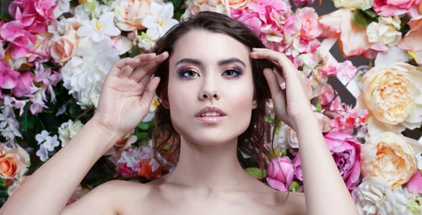 Retrato de menina da moda bonita, doce, sensual. Bela maquiagem e penteado romântico bagunçado. Fundo de flores. Olhos verdes . — Fotografia de Stock