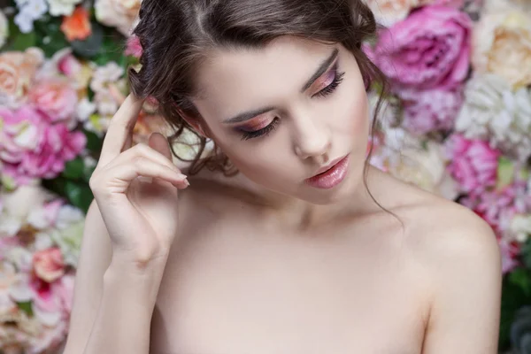 Retrato de menina da moda bonita, doce, sensual. Bela maquiagem e penteado romântico bagunçado. Fundo de flores. Olhos verdes . — Fotografia de Stock