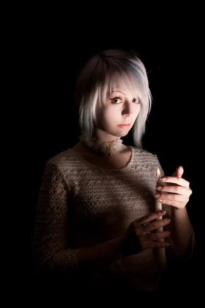 Teen girl in the dark with a candle, fear on her face, looking at the camera — Stock Photo, Image