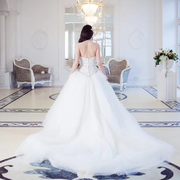 Hermosa novia. Vestido de novia con espalda abierta. Lujoso interior de luz — Foto de Stock