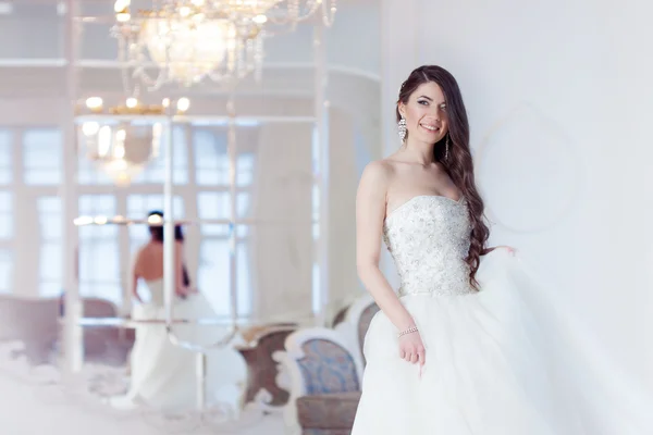 Porträt der schönen lachenden Braut. Hochzeitskleid mit offenem Rücken. luxuriöses helles Interieur — Stockfoto